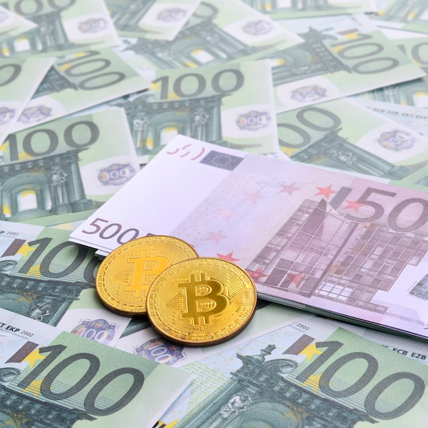 Des bitcoins physiques dorés reposent sur un ensemble de dénominations monétaires vertes de 100 euros