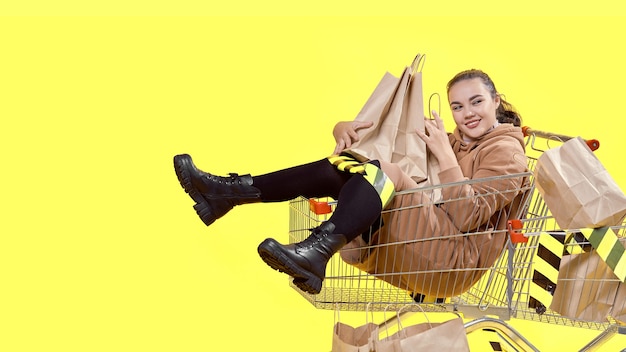 Black Friday, une fille est assise dans un panier et embrasse joyeusement des sacs à provisions