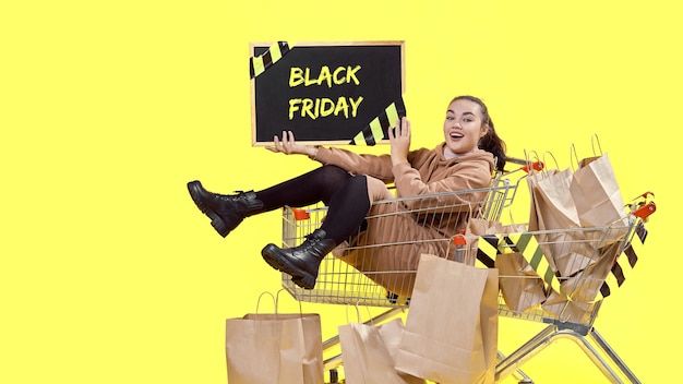 Black Friday, une fille est assise dans un panier et montre joyeusement le tableau