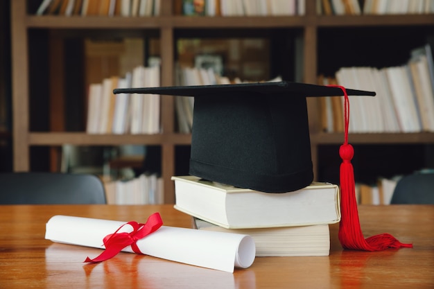 Black Graduation Cap avec Degré sur la table en bois dans la bibliothèque. Graduation