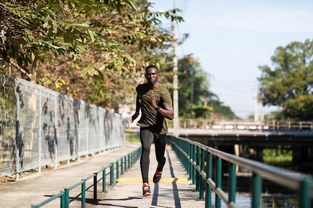 Black Man jogging et courir à côté de la route dans le parc au matin d'automne.