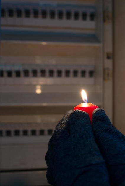 Blackout, debout avec une bougie devant une boîte à fusibles, coupure d'énergie, approvisionnement incertain