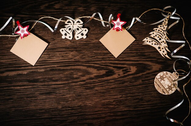 Blanc, photo, instantané, petit papier suspendu. Ornements d'arbre de Noël avec des rubans, des flocons de neige, des cloches sur fond de bois structurel brun. pose à plat. vue de dessus, cadre avec espace pour le texte. joyeuses fêtes