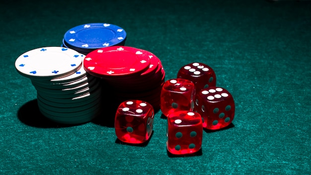 Photo blanc; pile de jetons de casino rouge et bleu avec des dés rouges sur fond vert