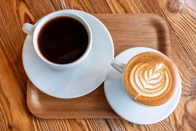 Blanc plat ou cappuccino et café filtre dans des tasses blanches sur une table en bois Différents styles de café boisson du matin au café sur un petit plateau en bois