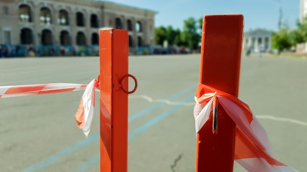 Le blanc rouge ne traverse pas le ruban et le poteau métallique. Ruban rouge et blanc de signal accroché à une clôture métallique, danger, avertissement. Ruban et poteau rouge en métal. La bande interdite entoure une zone dangereuse.