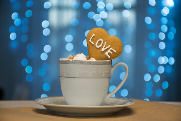 Blanc avec tasse de café en argent avec guimauve et cookie coeur avec mot d'amour sur les guirlandes bleues