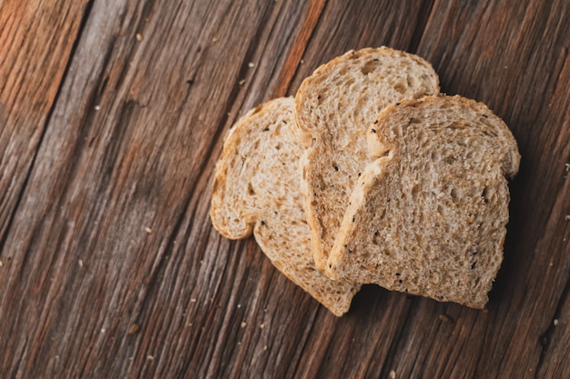 Blé entier, pain de grains entiers sur une planche en bois foncée, gros plan, vue de dessus