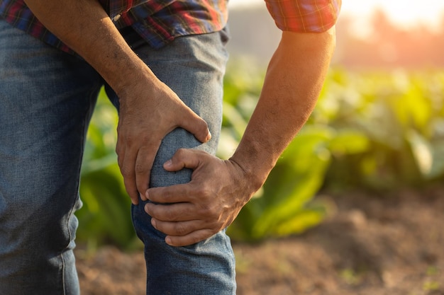 Blessures ou maladies pouvant survenir aux agriculteurs pendant le travail L'homme utilise sa main pour couvrir le genou à cause d'une douleur ou d'un malaise