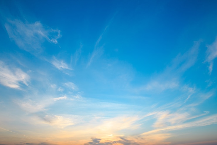 Bleu ciel et lumière orange du soleil à travers les nuages dans le ciel