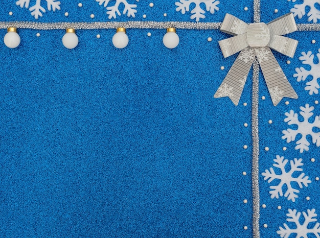 Bleu de Noël ou d'hiver avec des flocons de neige blancs, des boules, des perles, des guirlandes d'argent et un arc.