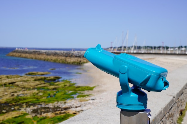 Bleu touristique payer pour voir le télescope payé par la côte dans l'horizon de la mer d'eau