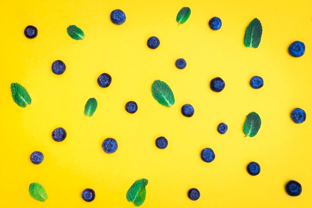 Bleuet mûr frais avec des feuilles de menthe sur fond jaune