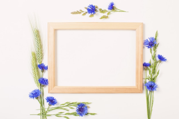 Photo bleuets bleus et céréales avec cadre en bois sur une surface blanche
