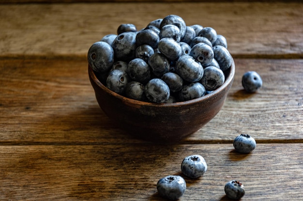 Bleuets dans une tasse en argile, sur une table en bois. Baies mûres dans la cuisine, récolte.