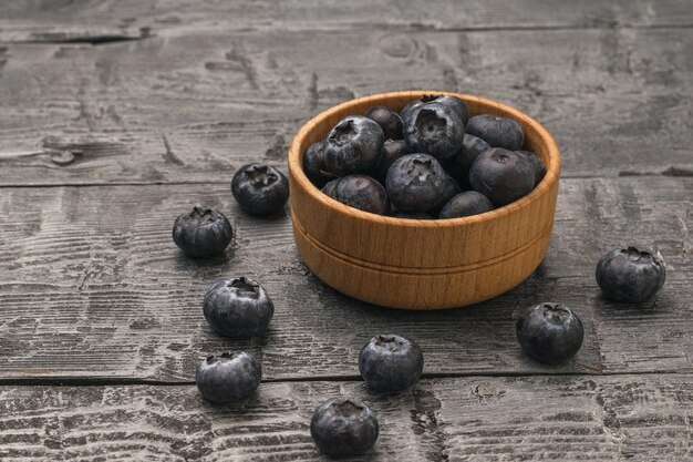 Bleuets dans une tasse en bois sur une table en bois.