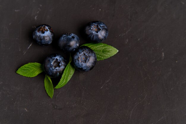 Les bleuets avec des feuilles vertes se trouvent sur une table sombre