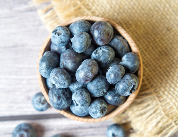 Bleuets fraîchement cueillis dans un bol en bois sur un fond en bois. Alimentation saine et nutrition. Place pour le texte.