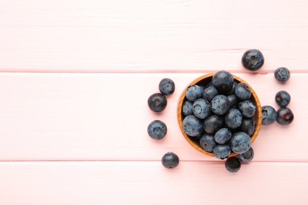 Bleuets frais dans un petit bol en bois sur fond rose