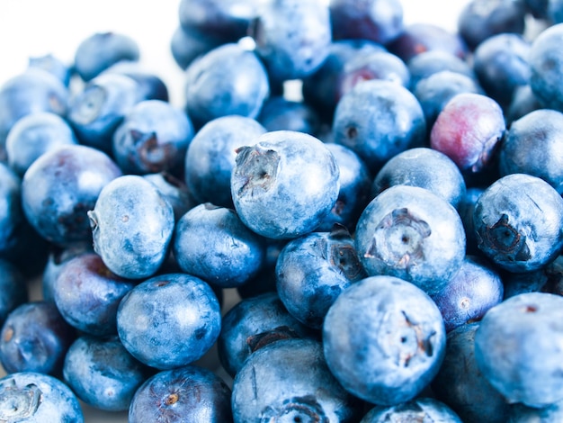 Bleuets frais du marché local sur fond blanc. Les myrtilles contiennent des anthocyanes et divers composés phytochimiques, qui peuvent jouer un rôle dans la réduction des risques de certaines maladies.