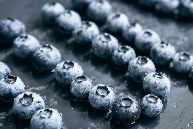 Photo des bleuets humides sur fond noir des baies de forêt avec des gouttes d'eau sur la table