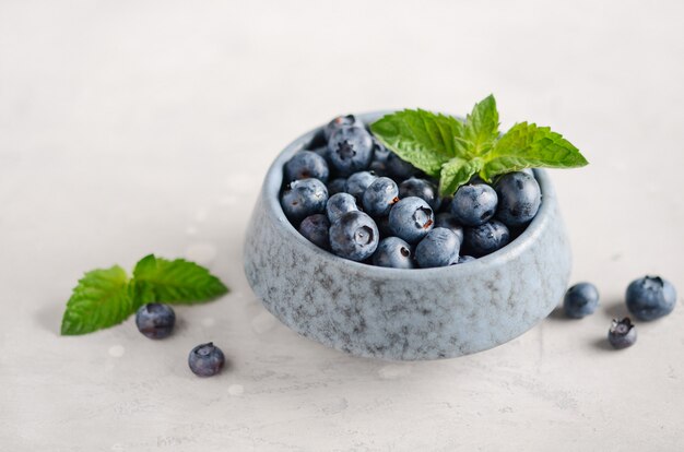 Bleuets mûrs dans un bol bleu sur un béton gris.