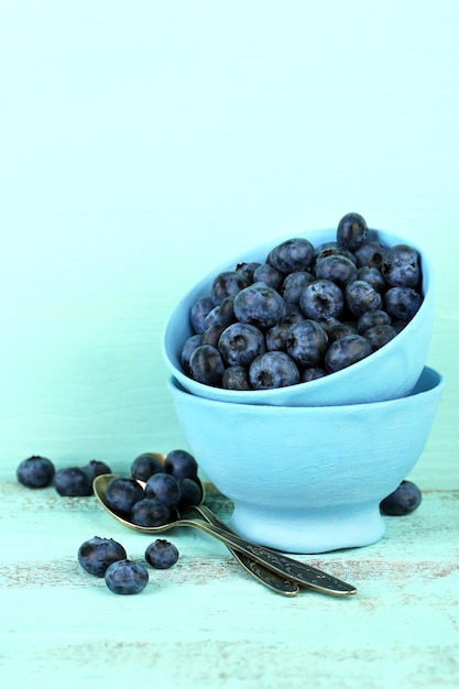 Bleuets mûrs savoureux dans des tasses sur une table en bois