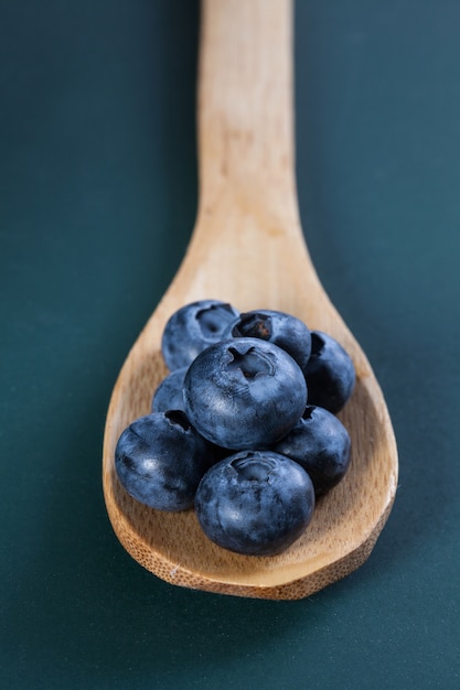 Bleuets placés sur une cuillère en bois et sur le tableau vert