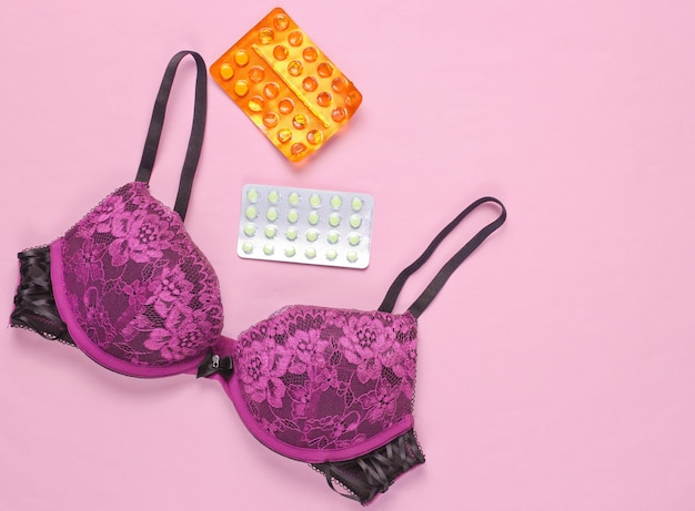 Blister de pilules contraceptives, soutien-gorge sexy sur fond rose. Vue de dessus