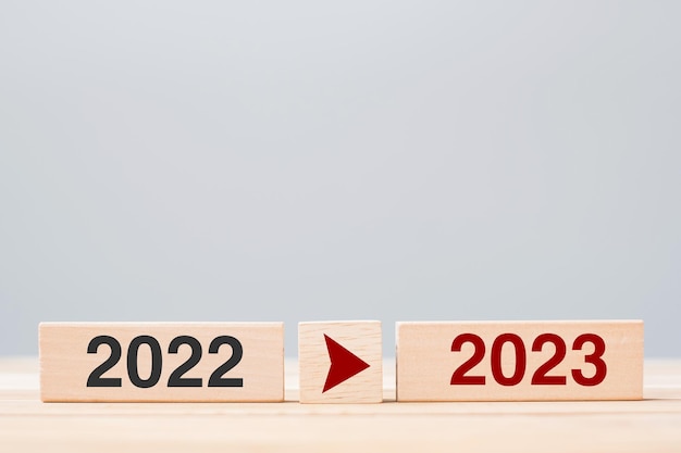 Bloc de bois 2023 et 2022 sur fond de table Changement d'objectif de compte à rebours de la stratégie de résolution et concepts de vacances du Nouvel An