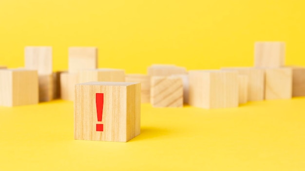 Bloc de bois avec signe d'exclamation sur un bloc de bois sur fond jaune avec symbole rouge de l'espace de copie