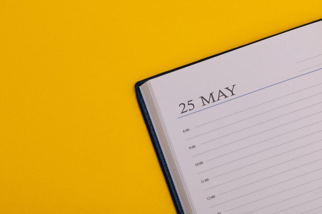 Photo bloc-notes ou agenda avec la date exacte sur fond jaune calendrier pour le printemps du 25 mai