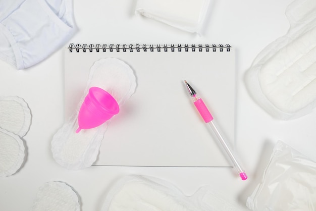 Bloc-notes avec des blocs-stylos coupe menstruelle et culotte sur copie blanche place de l'espace pour le texte Le concept de la menstruation des jours créatifs des femmes