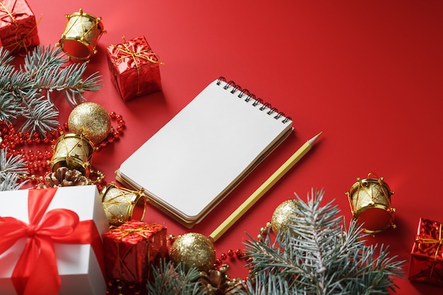 Bloc-notes et crayon pour écrire des souhaits et des cadeaux pour le Nouvel An et Noël autour des décorations de sapin de Noël