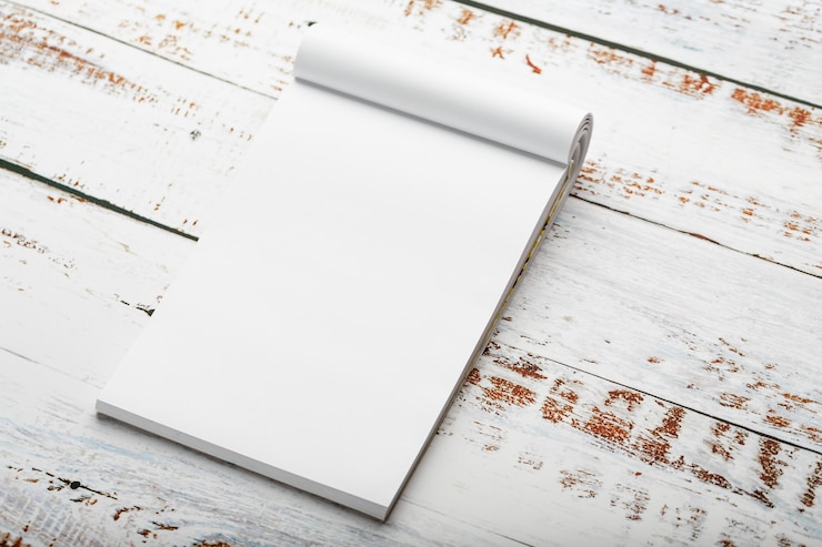 Photo bloc-notes avec un crayon rouge sur une table en bois blanche contre le