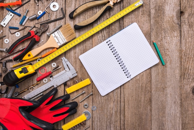 Bloc-notes entouré d'outils poussiéreux sur un vieux fond en bois.