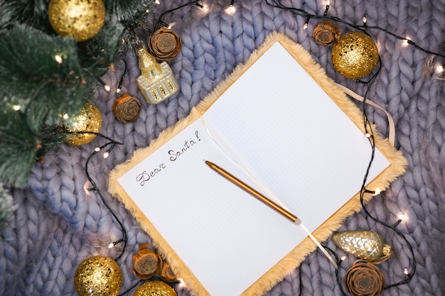 Bloc-notes avec l'inscription Cher Père Noël sur fond gris tricoté avec des décorations de Noël, flatlay