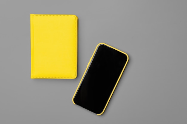 Bloc-notes jaune et smartphone sur fond gris