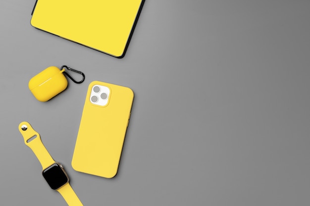 Bloc-notes jaune avec smartphone, smartwatch et écouteurs sur gris