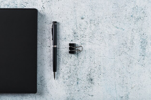 Photo bloc-notes noir avec un stylo noir sur fond gris. vue de dessus, concept minimaliste. espace libre.