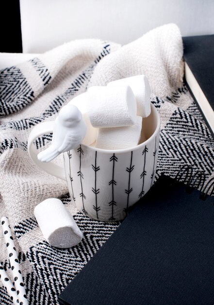 bloc-notes noir, tasse et plaid sur fond blanc