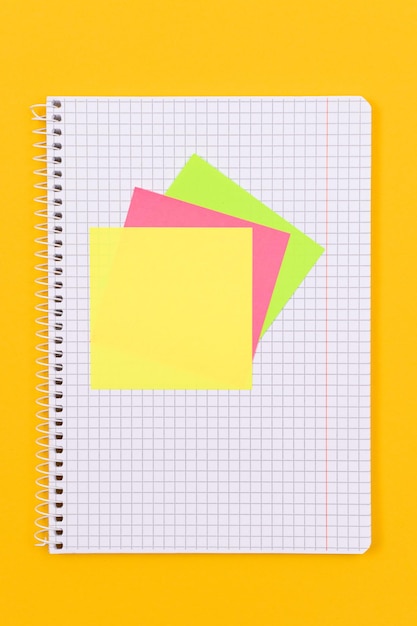 Un bloc-notes avec des notes autocollantes sur une table jaune