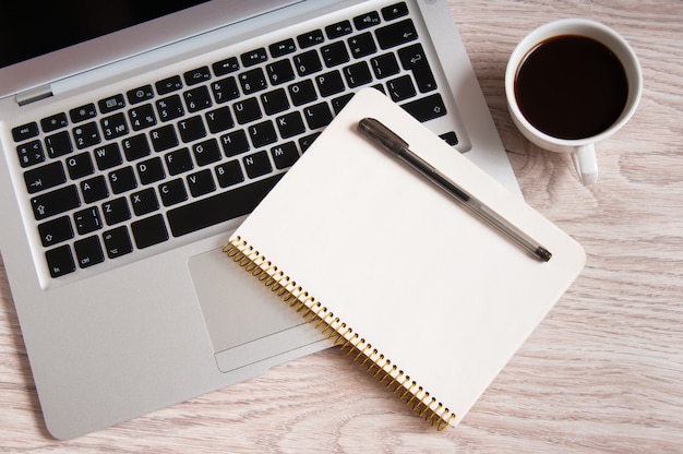 Bloc-notes, ordinateur portable et tasse à café sur table en bois