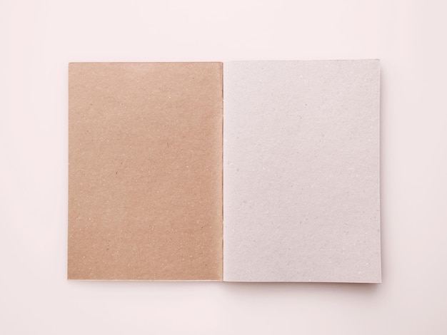 bloc-notes ouvert avec couverture artisanale marron et feuilles vides sur fond rose