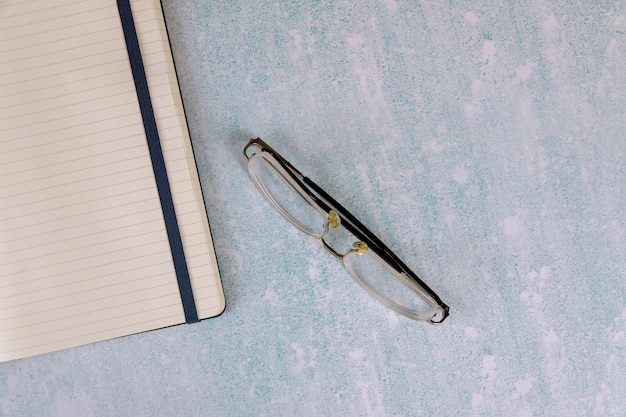 Bloc-notes ouvert vide sur les lunettes dans la table de bureau