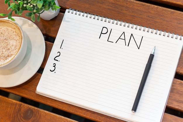 Bloc-notes avec le plan d'inscription et une tasse de café sur la table en bois