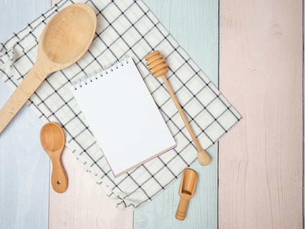 Bloc-notes sur une planche à découper avec des ustensiles de cuisine en bois sur l'espace de copie de recettes de cuisine de table