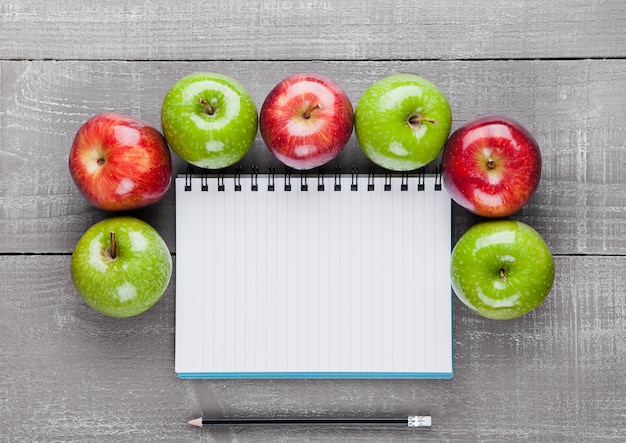 Bloc-notes avec des pommes saines comme idée de plan de régime sur planche de bois