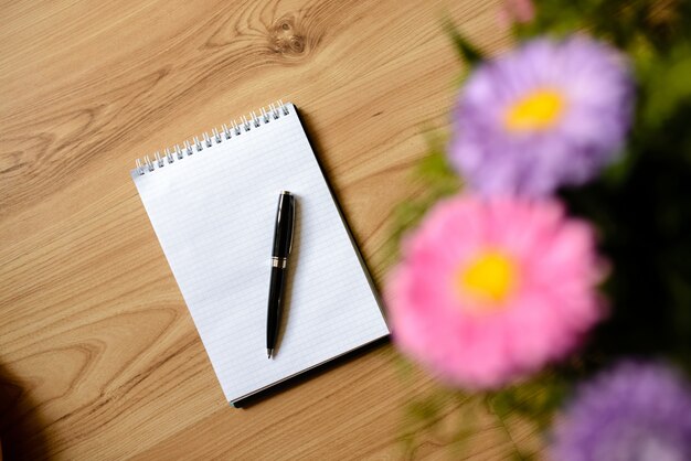 Bloc-notes pour les entrées avec des fleurs sur la table.