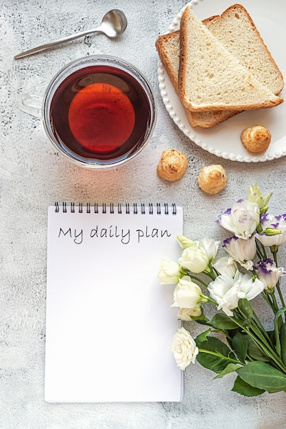 Un bloc-notes pour la planification quotidienne avec le cadre du petit-déjeuner et des fleurs